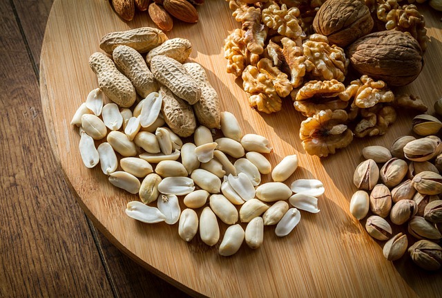Imagen de diversos frutos secos, incluyendo cacahuetes, nueces y pistachos, dispuestos sobre una tabla de madera.