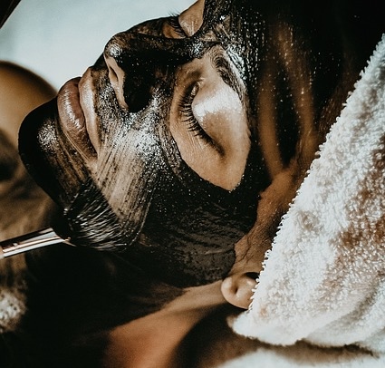 Imagen de una mujer relajada con una máscara facial en un spa, disfrutando de un tratamiento de cuidado de la piel.
